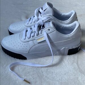 Puma White Sneakers with white soles. Black and gold accents. 
Never worn.